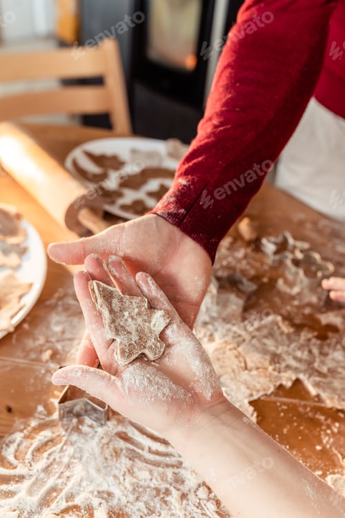 Preview: Family making homemade ginger cookies at kitchen together cutting different shapes of dough