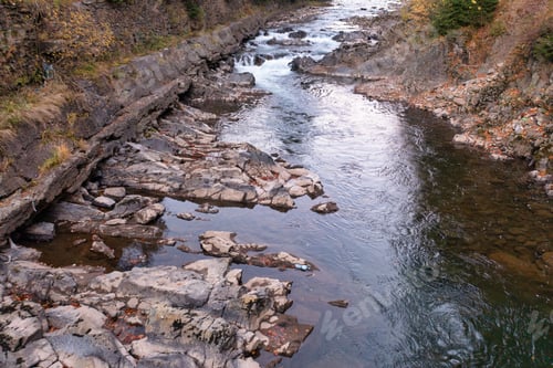 Preview: River stream running past mountain foot with autumn forest