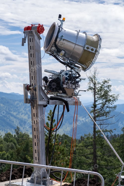 Preview: Yellow snow cannon on the edge of a hill overlooking valley in summer