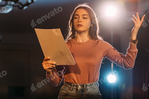 Preview: young actress reading scenario on stage in theatre
