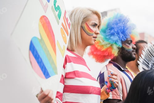 Preview: Gay people at LGBT pride parade while holding banner - Focus on lesbian girl face