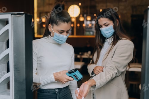 Preview: Woman measuring body temperature with contactless body thermometer