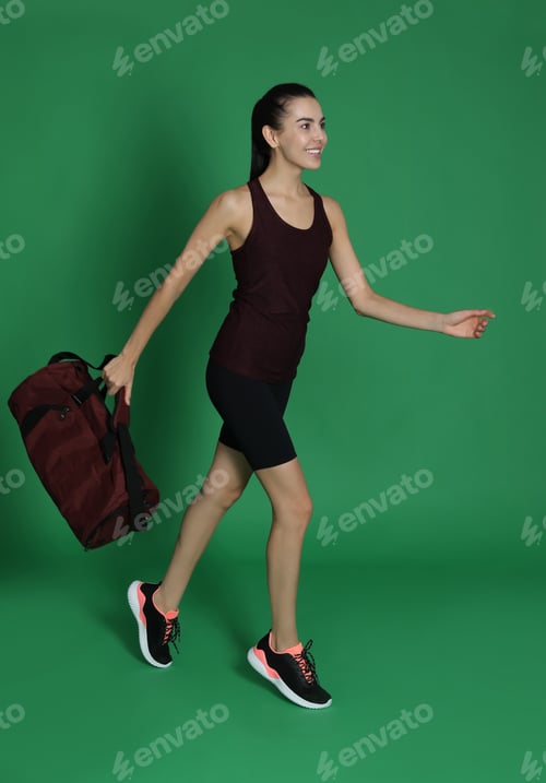 Preview: Beautiful woman with sports bag on green background