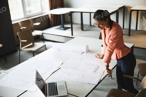 Preview: Young cheerful brunette female business analyst in glasses working with documents and laptop