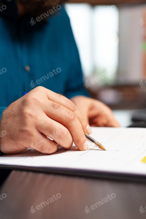 Preview: Closeup of businessman hand sitting at desk analyzing document with data chart