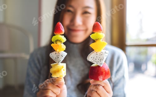 Preview: Woman Holding Fruit Skewers in Sunlight at Home
