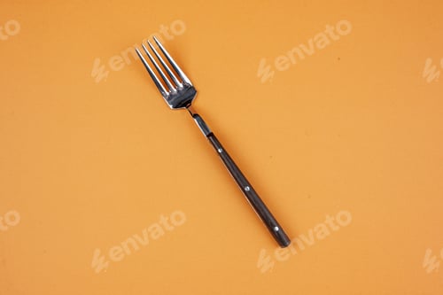 Preview: Overhead view of elegant metal fork in the middle on golden background with free space
