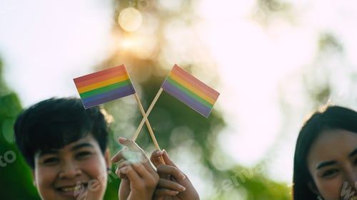 Preview: Cropped shot of young LGBT couples while showing/waving LGBT flag. LGBT happiness concept.