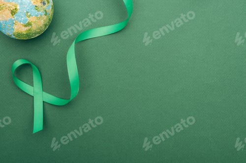 Preview: top view of green ribbon and toy earth on green background with copy space