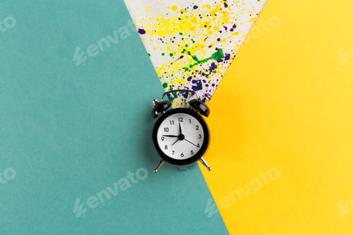 Preview: Vintage alarm clock on a creative colorful background with paint sprinkles