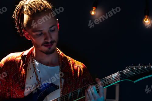 Preview: Young caucasian man musician playing guitar in the dark