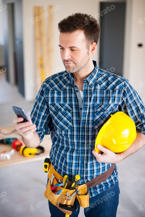 Preview: Construction worker using mobile phone during the working