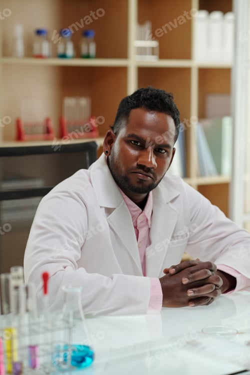 Preview: Young serious African American scientist in lab coat looking at camera