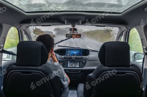 Preview: Rain on windshield as wiper clears view. Visible road.