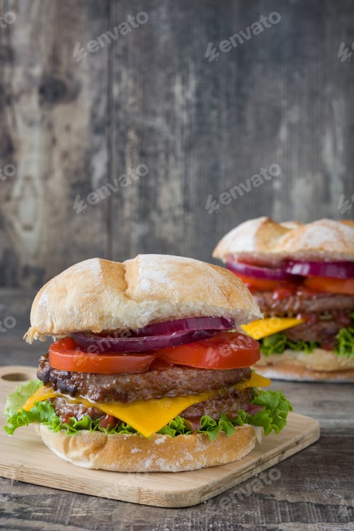Preview: Two delicious burgers resting on wooden board, featuring beef patties, cheese, and fresh vegetables