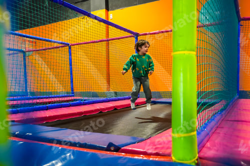 Preview: Child jumping and having fun on colorful trampoline in indoor playground