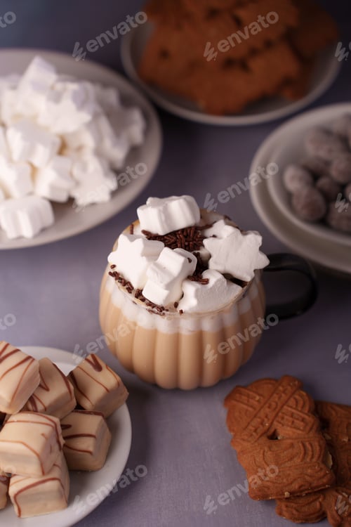 Preview: Cozy winter treats: hot chocolate with marshmallows, cookies, and sweets on a purple table setting.