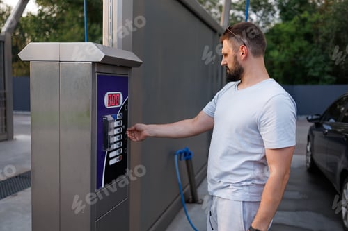 Preview: After payment, the man selects the car wash mode. A car at a self service car wash.