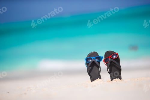 Preview: Summer black flip flops with sunglasses on white beach