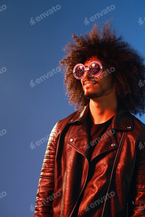 Preview: Portrait of a stylish man with curly hair with glasses smile on blue background multinational, color