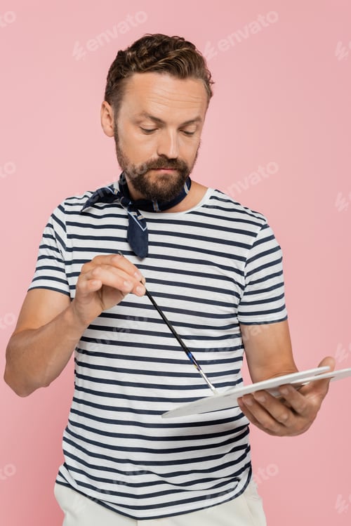 Preview: bearded french artist with neck scarf holding palette and paintbrush isolated on pink