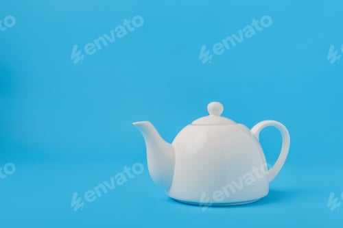 Preview: White ceramic teapot isolated on blue background.