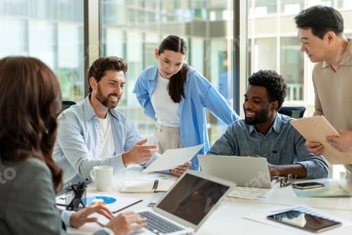 Preview: Diverse business team collaborating on project using laptop and documents in modern office