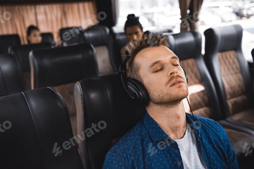 Preview: adult man in headphones listening music and sleeping during trip on bus