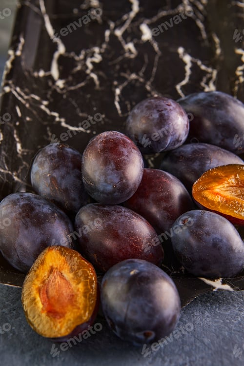 Preview: Still life of plums in a marble tray on a purple background