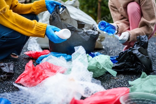 Preview: Close-up of young women girls hands sorting recyclable plastic bottles into trash bags outdoors