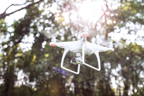 Preview: Flying helicopter drone with camera. Green sunny nature.