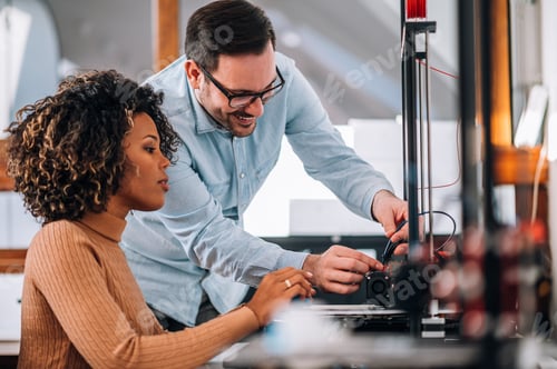 Preview: Technology, people and engineering concept. Handsome man learning woman how to use 3D printer.