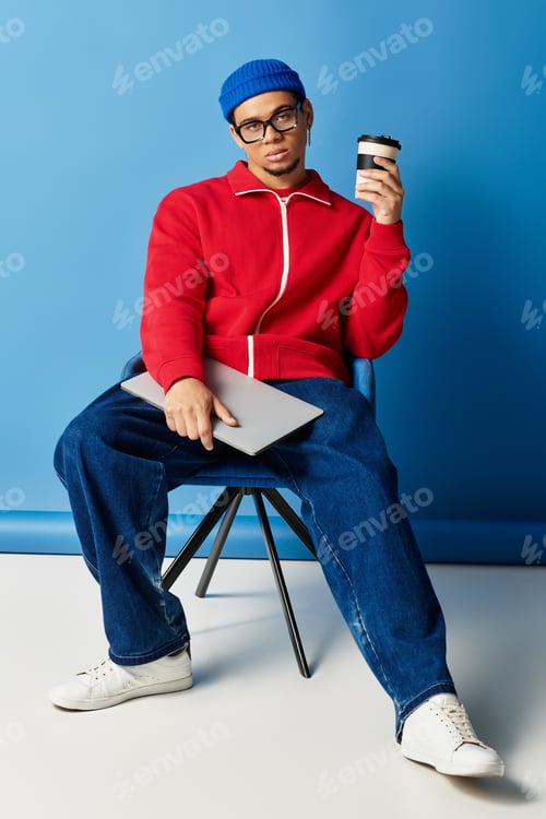 Preview: Stylish young man in beanie poses confidently against a vibrant blue backdrop