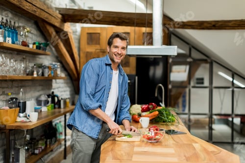 Preview: Happy handsome man cooking in kitchen at home