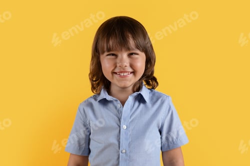 Preview: Kids happiness. Close up portrait of cute little boy smiling widely to camera, posing over orange