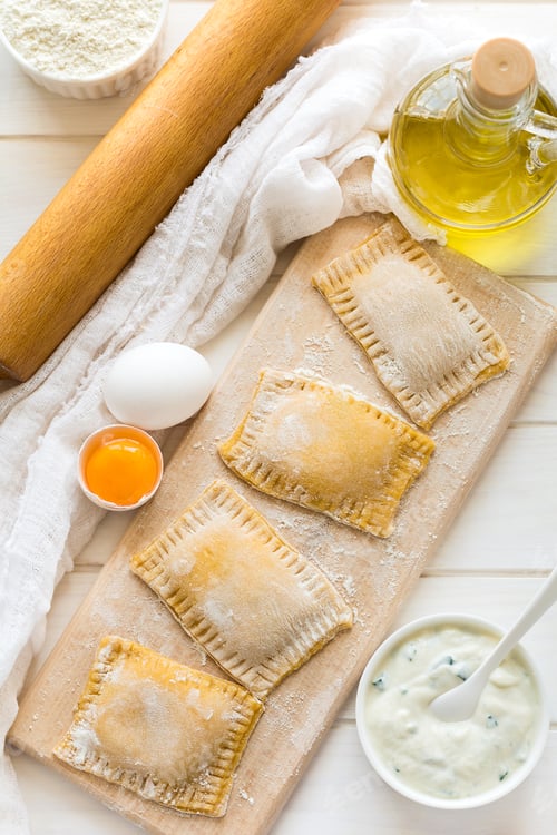 Preview: Fresh ravioli with spinach and ricotta waiting to be cooked on wooden table. Selective focus
