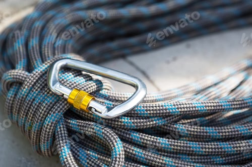 Preview: Coiled climbing rope and steel carabiner. Mountain climbing equipment: carbine, harness