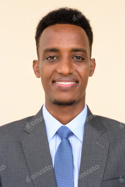 Preview: Face of handsome African businessman wearing suit and tie against plain background