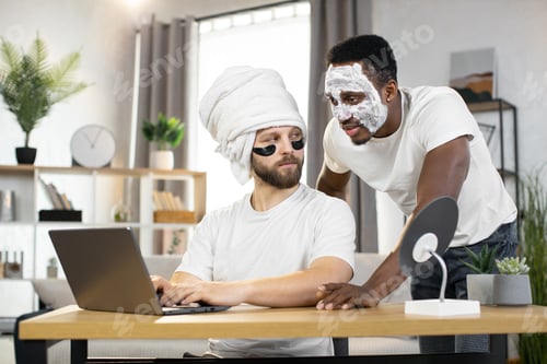 Preview: Young gay multiethnic couple, having cosmetic procedures, working on a laptop at home
