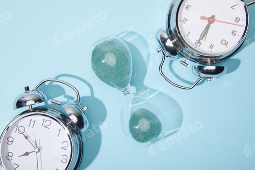 Preview: top view of classic alarm clocks and hourglass on blue background