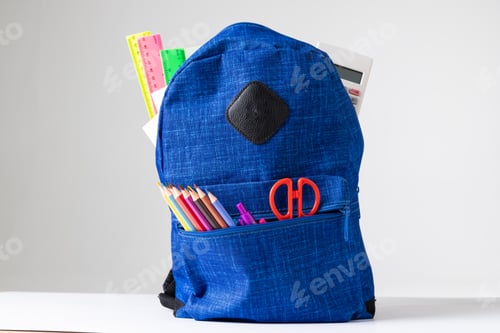Preview: Vertical image of backpack with school equipment on white surface