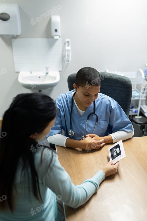 Preview: Mixed-race female doctor discussing baby ultrasound report with pregnant woman