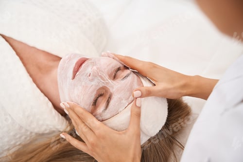Preview: Woman lies on cosmetology couch with serum on her face