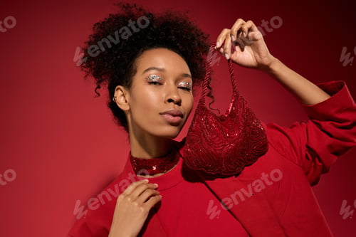 Preview: Beautiful young woman showcasing a sparkling red garment against a vibrant crimson backdrop