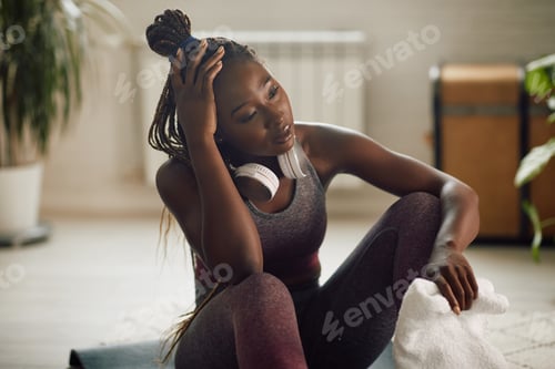 Preview: Tired black sportswoman taking a break while exercising at home.