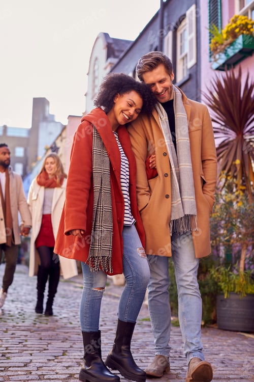 Preview: Multi Cultural Couple With Friends Walking Along Residential City Street In Fall Or Winter