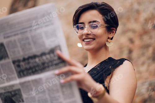 Preview: Portrait of a woman with eyeglasses reading newspaper outside