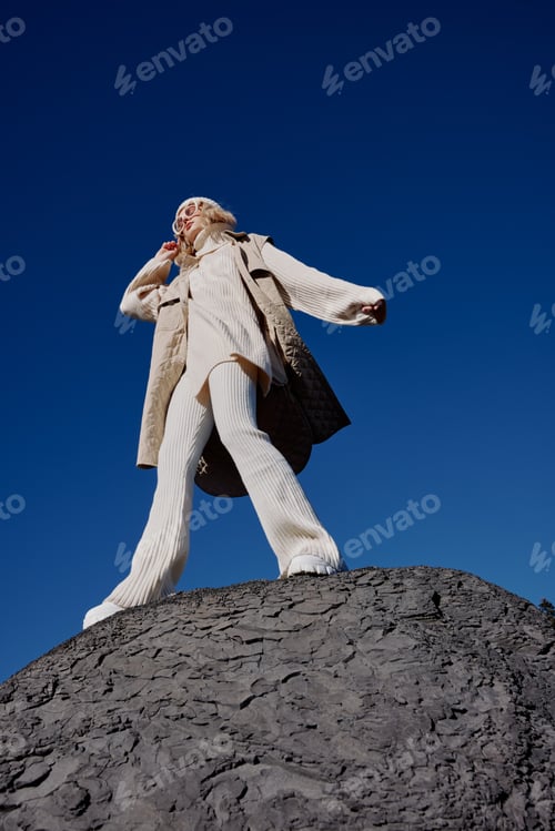 Preview: woman in autumn clothes stands on a rock landscape blue sky relaxation