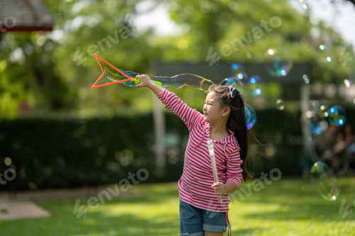 Preview: Smiling Girl Playing with Bubbles on a Sunny Day Outdoors