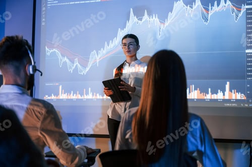 Preview: Female leader talking to employees, showing the plan on the projector in office of stock